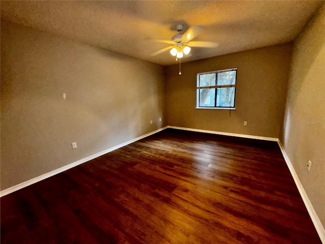 empty room with ceiling fan, a textured ceiling, baseboards, and wood finished floors