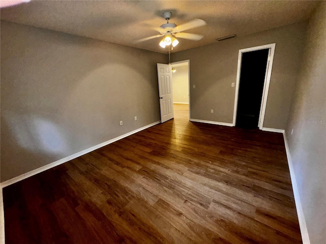 unfurnished bedroom with ceiling fan, a textured ceiling, dark wood-style flooring, visible vents, and baseboards