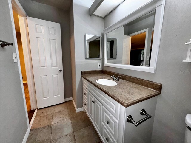 bathroom featuring tile flooring, toilet, and vanity with extensive cabinet space