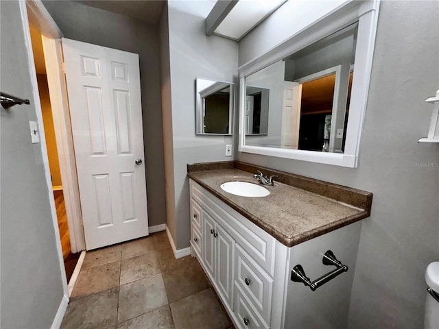 bathroom featuring toilet, vanity, and baseboards