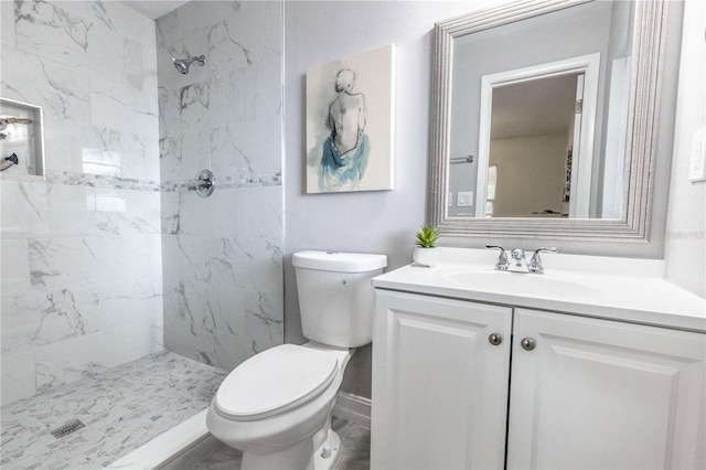 bathroom with a tile shower, vanity, and toilet