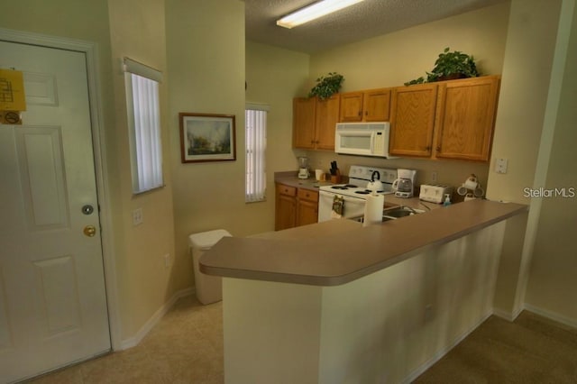 kitchen featuring a textured ceiling, kitchen peninsula, a healthy amount of sunlight, and white appliances