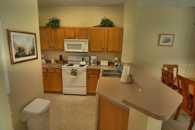 kitchen featuring kitchen peninsula, light tile patterned floors, white appliances, and sink