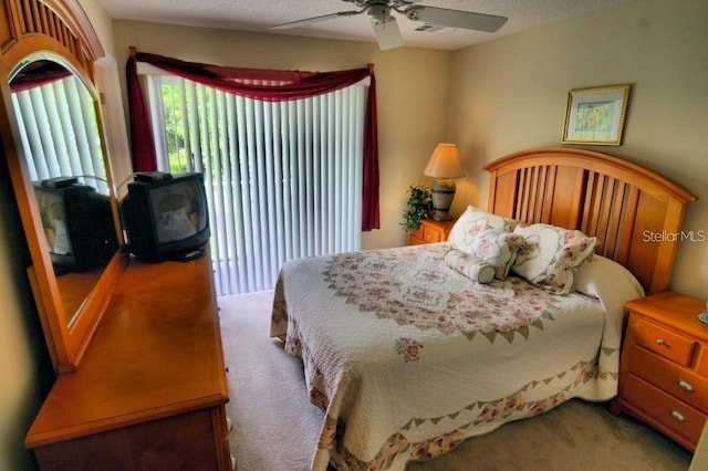 carpeted bedroom featuring ceiling fan and a textured ceiling