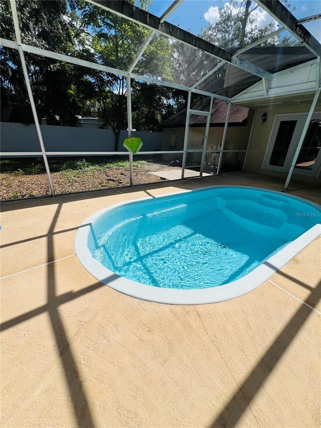 view of pool with glass enclosure, a patio, fence, and a fenced in pool