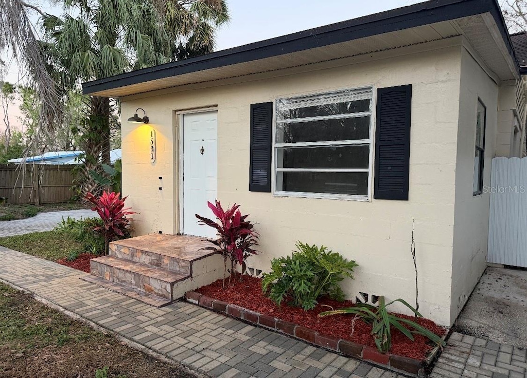 property entrance with fence and stucco siding