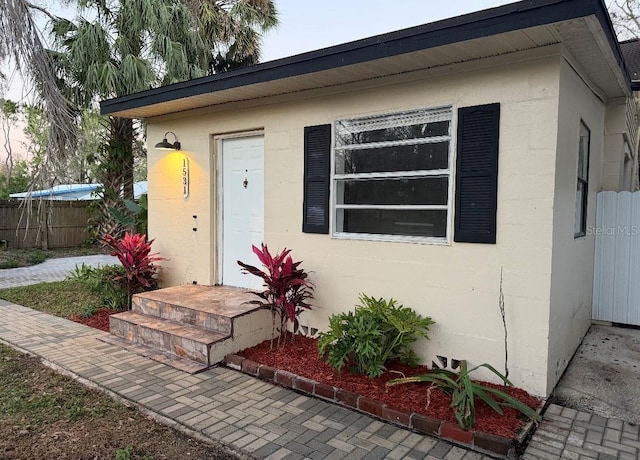 property entrance with fence and stucco siding