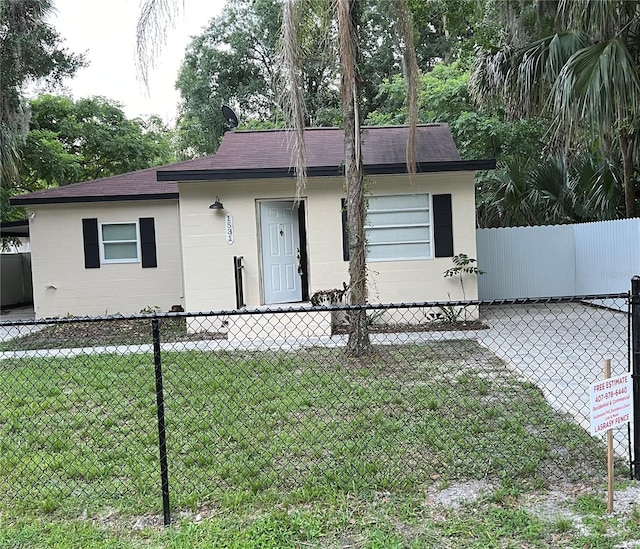 view of front of property with concrete block siding, fence, and a front lawn