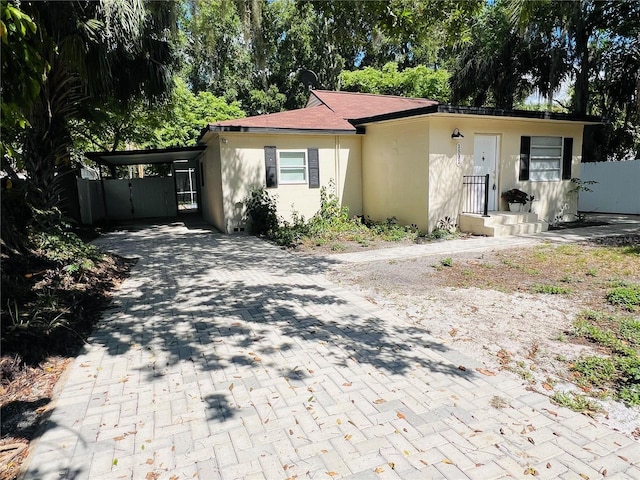 ranch-style home with a carport, fence, decorative driveway, and stucco siding