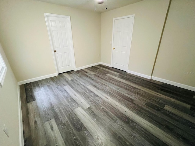 spare room featuring baseboards and dark wood finished floors