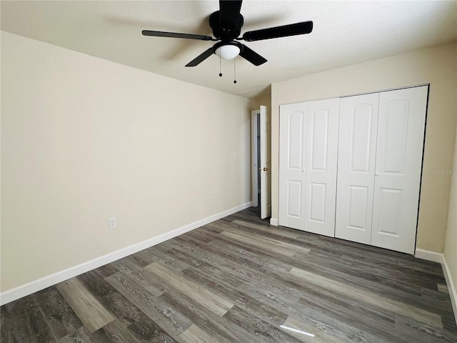 unfurnished bedroom featuring dark wood-style floors, a closet, ceiling fan, and baseboards