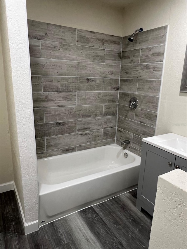 bathroom featuring bathtub / shower combination, vanity, baseboards, and wood finished floors