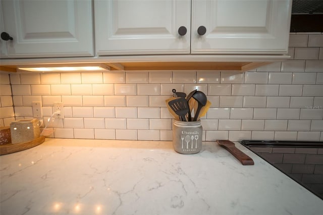 details with backsplash, white cabinetry, and light stone counters