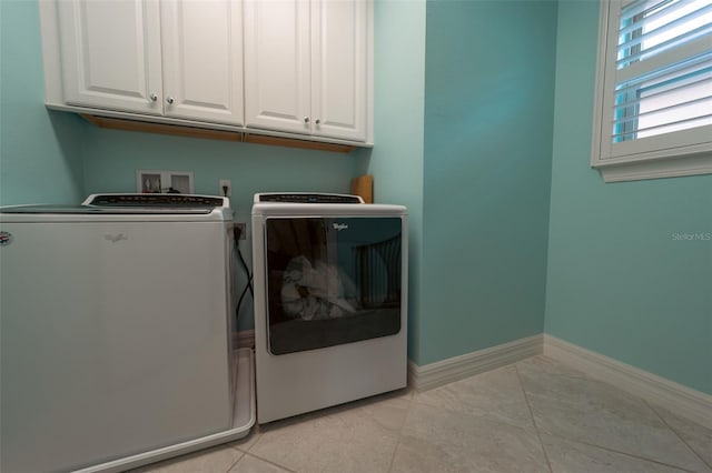 clothes washing area with light tile patterned flooring, cabinets, and independent washer and dryer