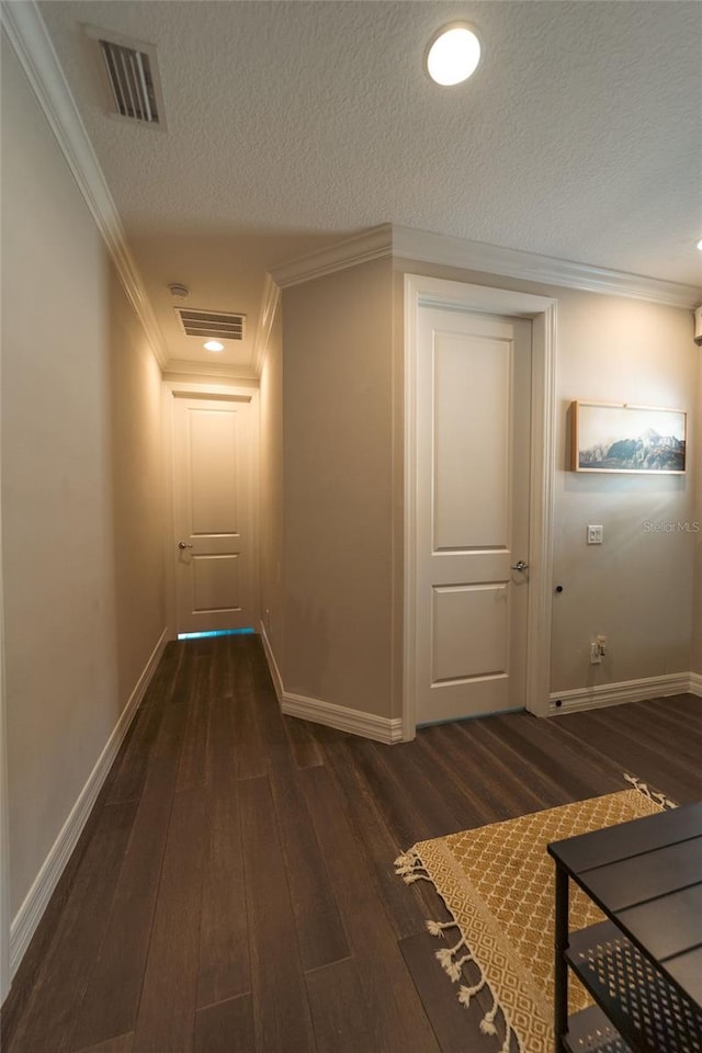 corridor with crown molding, dark hardwood / wood-style flooring, and a textured ceiling