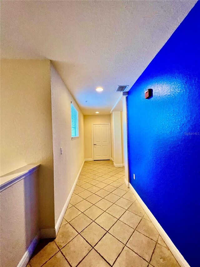 hallway featuring a textured ceiling and light tile floors