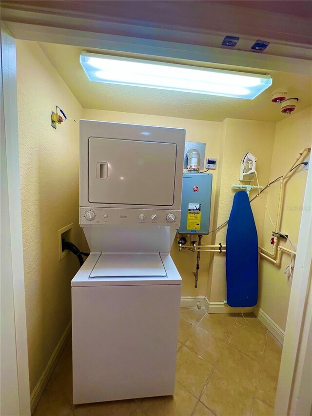 laundry area with stacked washer and dryer, hookup for a washing machine, tankless water heater, and light tile floors