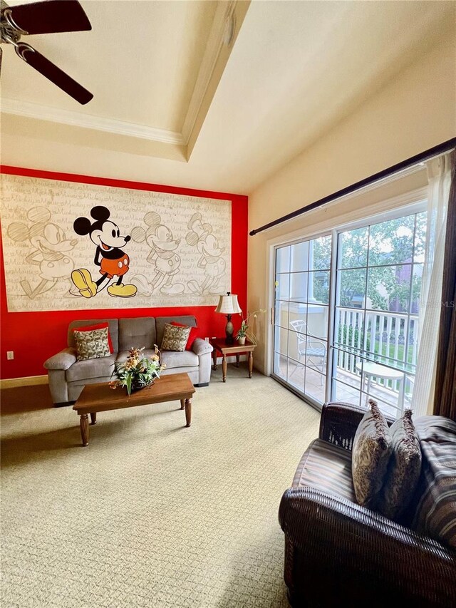 living room with a raised ceiling, ornamental molding, ceiling fan, and carpet floors