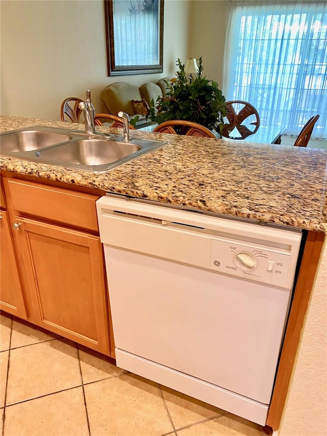 kitchen with light stone counters, sink, dishwasher, and light tile floors