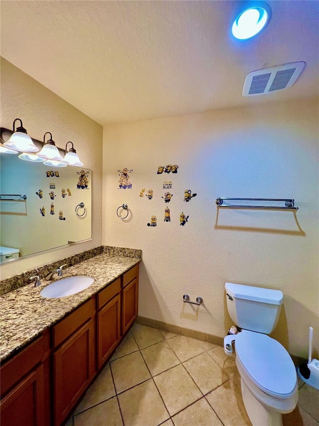 bathroom with a textured ceiling, vanity, toilet, and tile floors