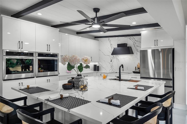 kitchen featuring light stone countertops, white cabinetry, stainless steel appliances, a kitchen breakfast bar, and beamed ceiling