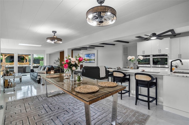 dining space featuring ceiling fan, sink, and light tile patterned flooring