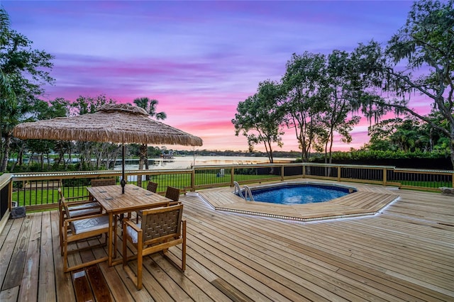 deck at dusk featuring a water view