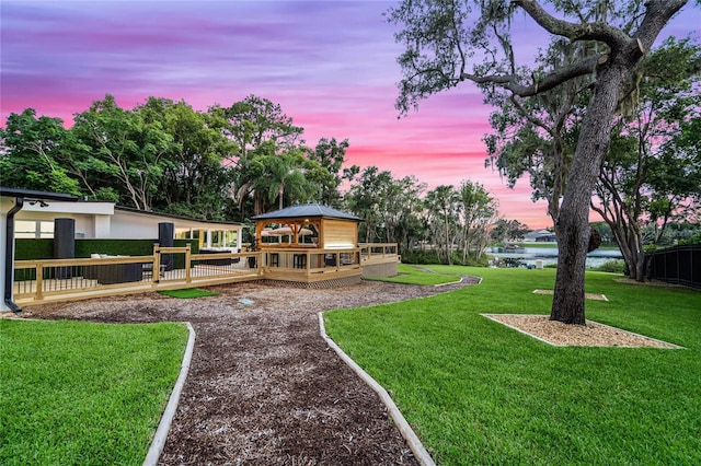 yard at dusk featuring a gazebo and a deck with water view