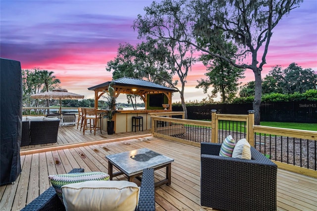 deck at dusk with a gazebo and exterior bar