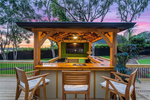 deck at dusk with exterior bar and a gazebo