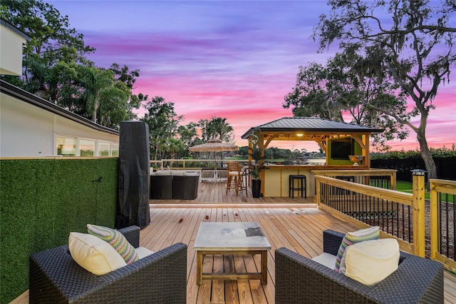 deck at dusk with exterior bar, a gazebo, and outdoor lounge area