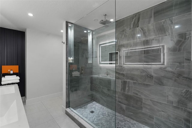 bathroom with tile patterned flooring, vanity, a tile shower, and a textured ceiling