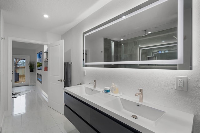 bathroom with tile patterned floors, vanity, a textured ceiling, and walk in shower