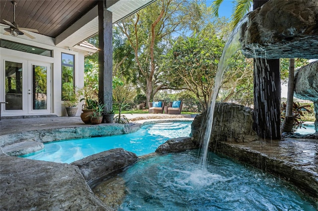 view of swimming pool with ceiling fan and french doors