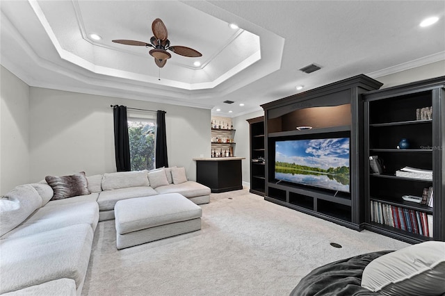 living room with carpet floors, a raised ceiling, ceiling fan, and ornamental molding