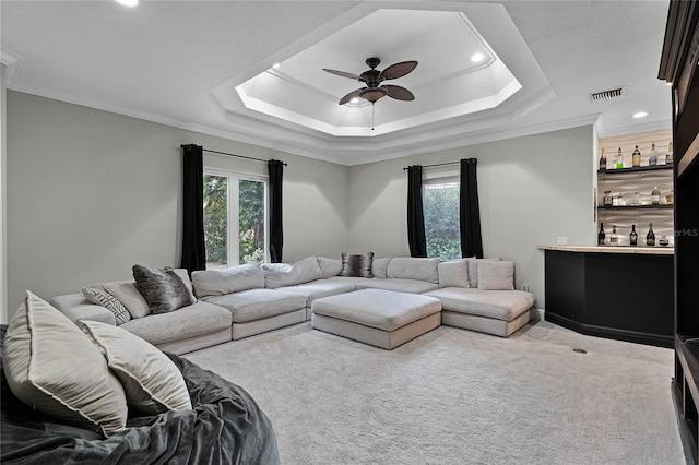 living room featuring carpet floors, a raised ceiling, ceiling fan, and crown molding