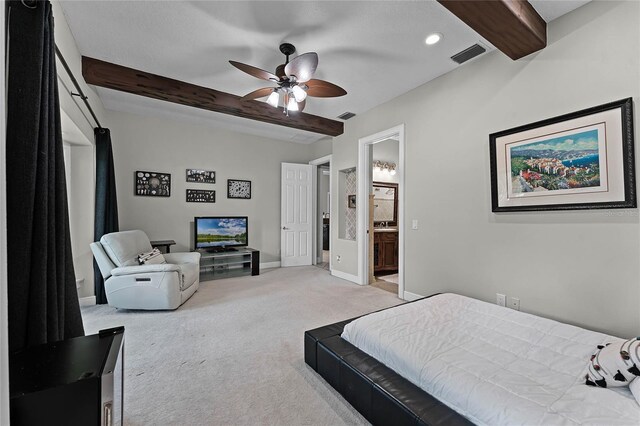 carpeted bedroom featuring ceiling fan, beam ceiling, and ensuite bathroom