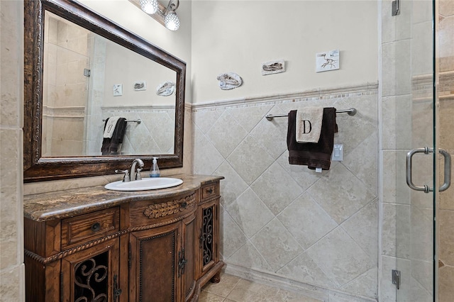 bathroom with tile patterned floors, vanity, a shower with shower door, and tile walls