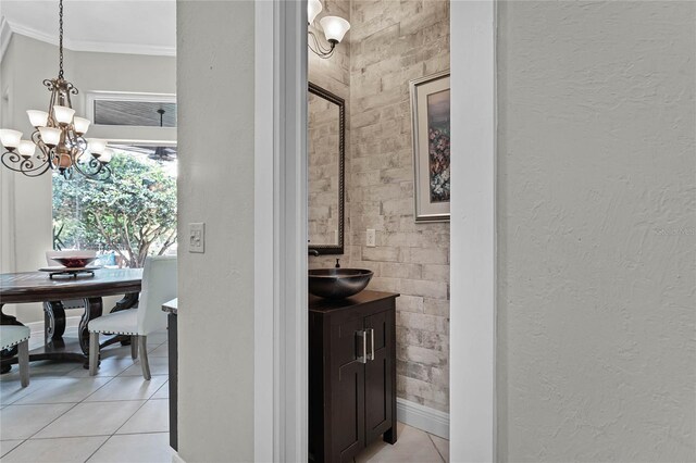 interior space with tile patterned floors, vanity, crown molding, and an inviting chandelier