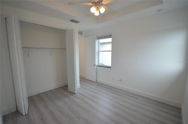 unfurnished bedroom featuring baseboards, wood finished floors, visible vents, and a closet