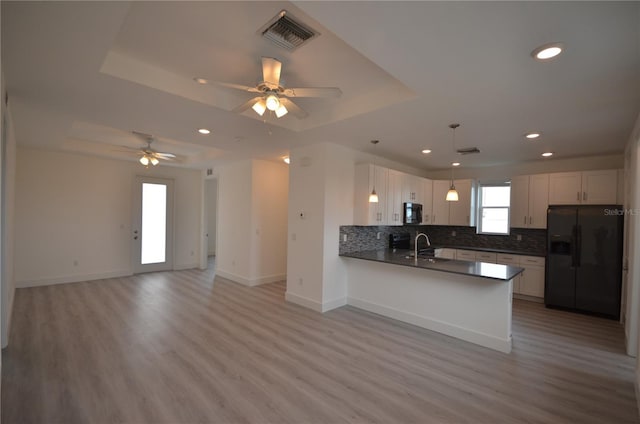 kitchen featuring a tray ceiling, dark countertops, visible vents, a sink, and black appliances