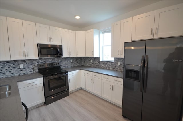 kitchen with stainless steel microwave, light wood-style floors, white cabinetry, black refrigerator with ice dispenser, and range with electric stovetop