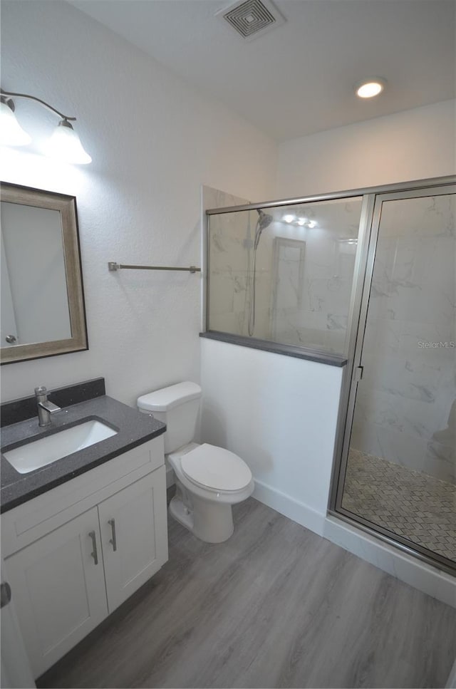 full bath featuring wood finished floors, visible vents, toilet, and a marble finish shower