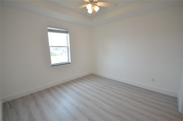 unfurnished room featuring baseboards, a ceiling fan, wood finished floors, and a raised ceiling
