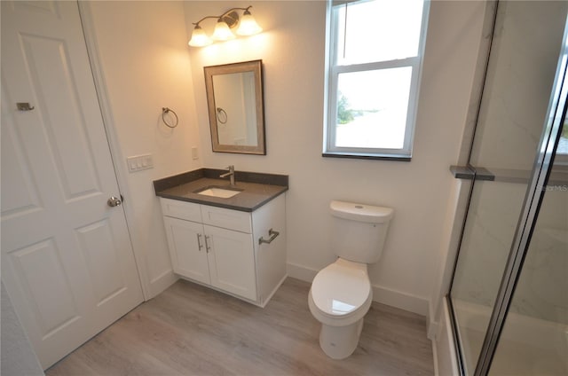 full bathroom featuring wood finished floors, an enclosed shower, toilet, vanity, and baseboards