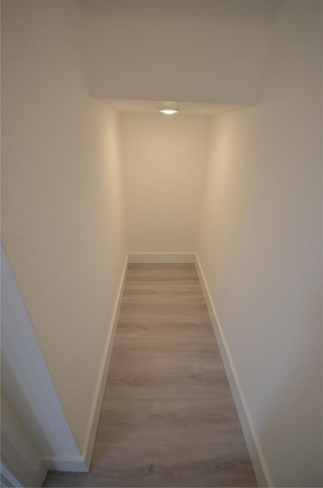 hallway with wood finished floors and baseboards