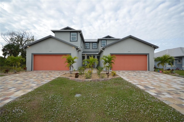 traditional-style home featuring a garage, stucco siding, and decorative driveway