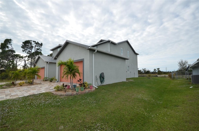 view of home's exterior featuring a yard, an attached garage, stucco siding, and driveway
