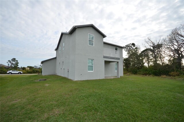 view of property exterior with a lawn, a balcony, and stucco siding