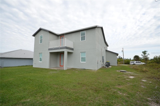 back of property with stucco siding, a yard, central AC unit, and a balcony